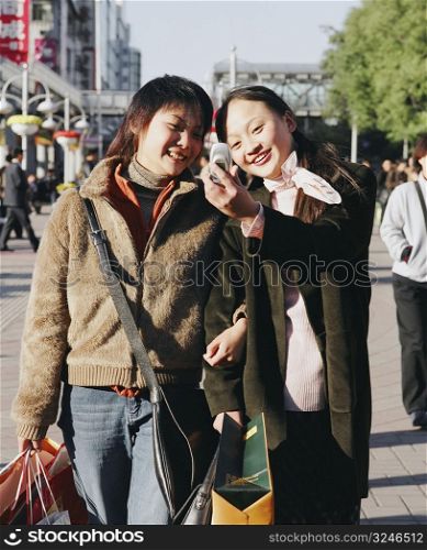 Two young women looking at a mobile phone and smiling