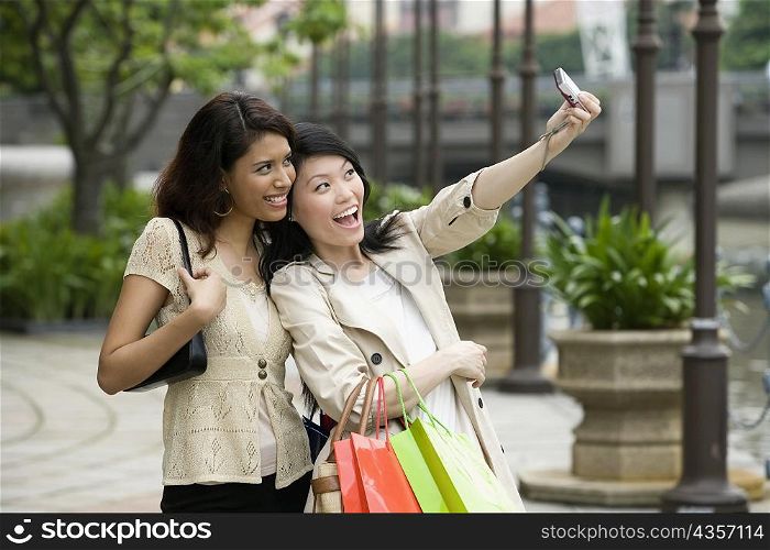 Two young women photographing themselves with a digital camera