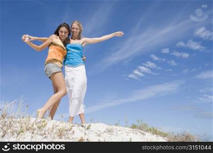 Two young women posing on a sand hill