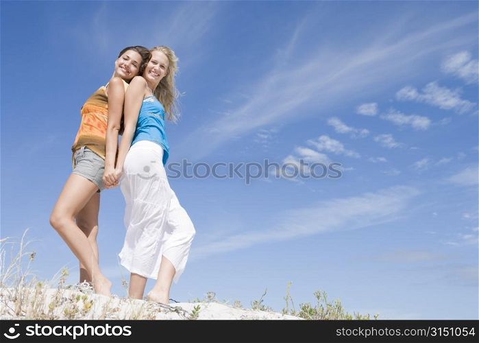 Two young women posing on a sand hill