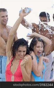 Two young women pouring water on their heads with a young man and a mid adult man standing behind them