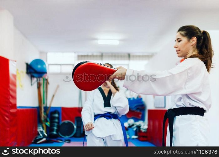 Two young women practice taekwondo in a training center