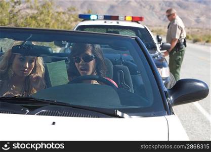 Two young women reading speeding ticket in car