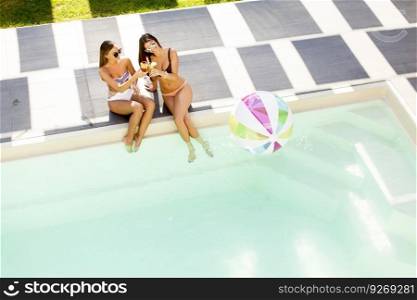 Two young women relaxing by the swimming pool on a sunny day