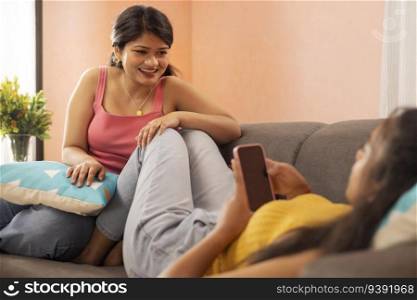 Two young women relaxing on sofa in living room