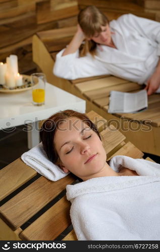 Two young women relaxing on wooden chair at luxury spa