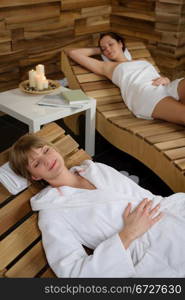 Two young women relaxing on wooden chair at luxury spa