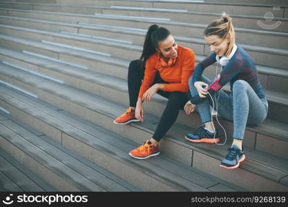 Two young women resting after doing sports outdoors on stairs