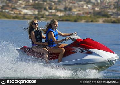 Two young women riding jetski on lake