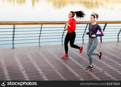 Two young women running by river in the morning