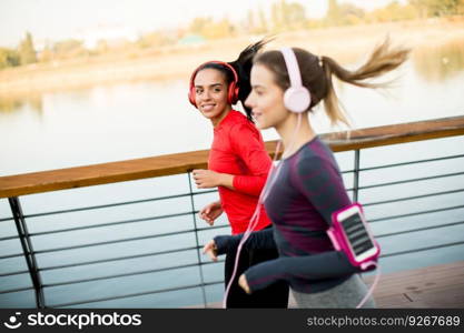 Two young women running by the river in the morning