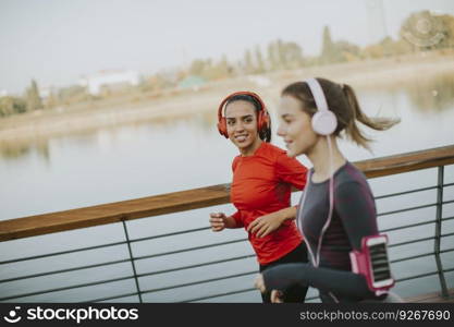 Two young women running by the river in the morning