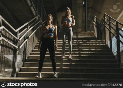 Two young women running in urban enviroment by day