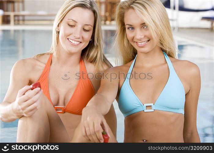 Two young women sitting at the poolside