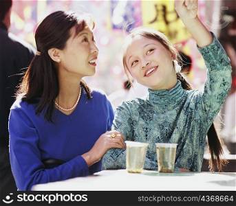 Two young women sitting in a restaurant and looking up