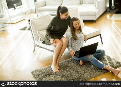 Two young women sitting in a room and using laptop