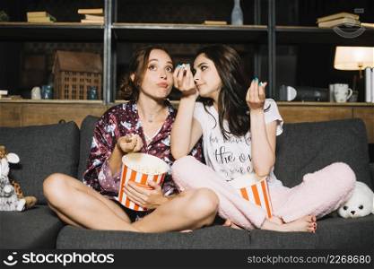 two young women sitting sofa watching television
