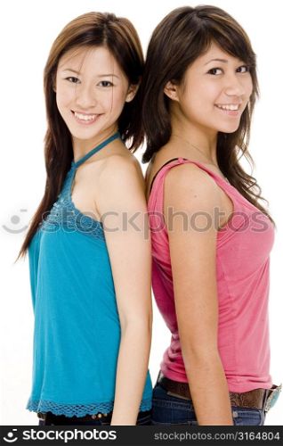 Two young women standing back to back and smiling
