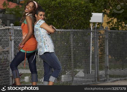 Two young women standing back to back and smiling