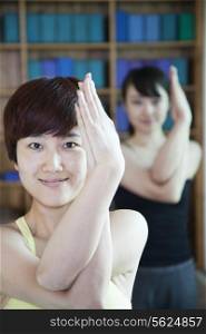 Two young women stretching and doing yoga, close-up, looking at camera