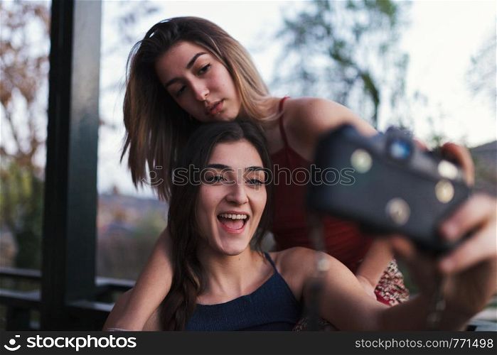 Two young women take a selfie on the balcony at evening