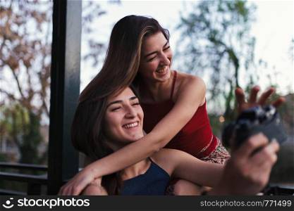 Two young women take a selfie on the balcony at evening