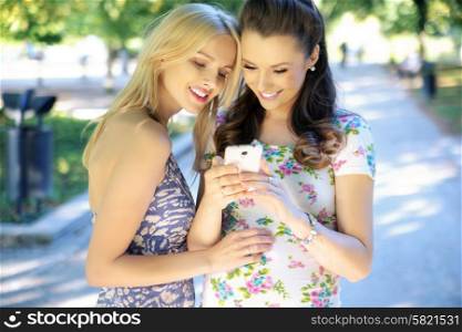 Two young women texting their girlfriend