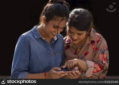 Two young women using mobile phone together