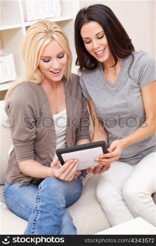Two Young Women Using Tablet Computer At Home on Sofa