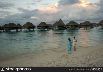 Two young women walking on a beach, Moorea, Tahiti, French Polynesia, South Pacific