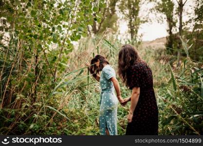 Two young women walking through the field the field wearing dresses and sneakers