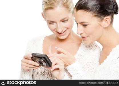 two young women watching pictures on digital camera, isolated on white