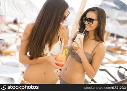 Two young women with drinks at the beach