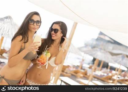 Two young women with drinks at the beach