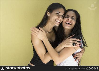 Two young women with long hair embracing and making funny faces