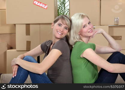 twosome of young girls moving in together sitting back-to-back