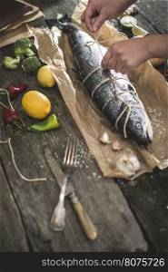 Tying a rope on fish for grilling. Baking paper