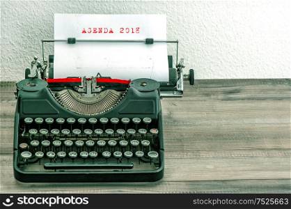 Typewriter with white paper page on wooden desk. Business concept. Sample text AGENDA 2018. vintage style picture
