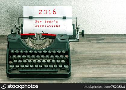 Typewriter with white paper page on wooden table. sample text 2016 New Year&rsquo;s Resolutions. Vintage style toned picture
