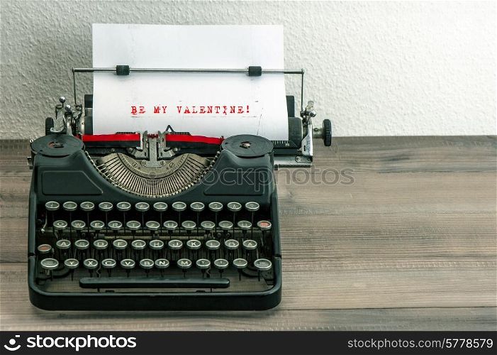 typewriter with white paper page on wooden table. sample text Be My Valentine!