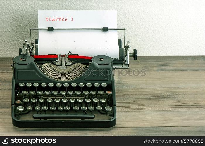 typewriter with white paper page on wooden table. sample text Chapter 1