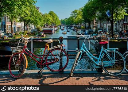 Typical Amsterdam view - Amsterdam canal with boats and bicycles on a bridge. Amsterdam, Netherlands. Amsterdam canal with boats and bicycles on a bridge