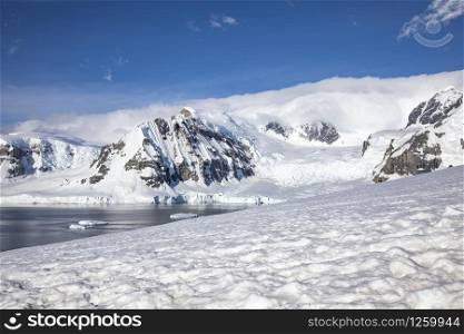 Typical Antarctic landscape with mountain snow covered and iceberg floating in sea