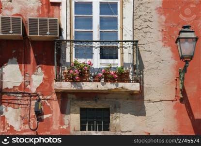 typical balcony of a residential window building with flowers, antique air conditioner and wall lamp in Lisbon, Portugal