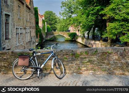 Typical Belgian scenic cityscape Europe tourism and bicycle transport concept - bicycle on a bridge near canal and old house. Bruges (Brugge), Belgium. Bicyccle on a bridge near canal and old houses. Bruges Brugge , Belgium
