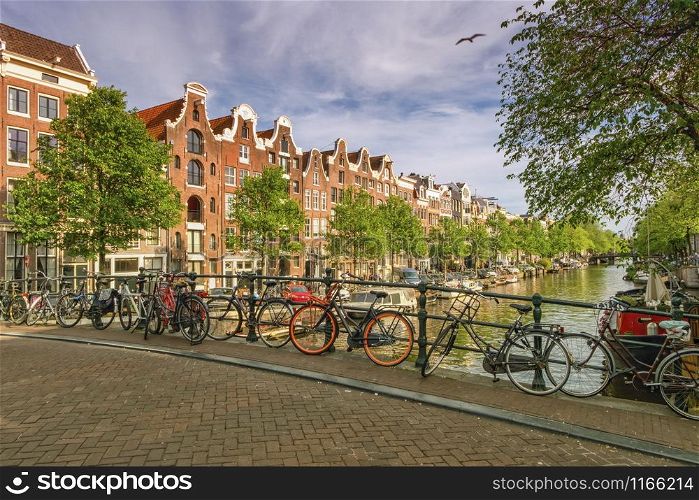 Typical buildings, canal and bikes in Amsterdam by day, Netherlands. Typical buildings, canal and bikes in Amsterdam, Netherlands