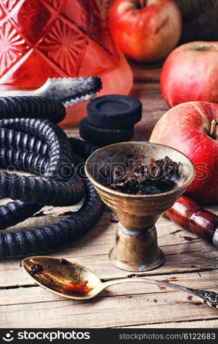 Typical details of smoking hookah on a wooden background. Hookah with apple flavor