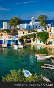 Typical Greece scenic island view - small harbor with fishing boats in crystal clear turquoise water, traditional white houses church. Mandrakia village, Milos island, Greece.. Mandrakia village in Milos island, Greece