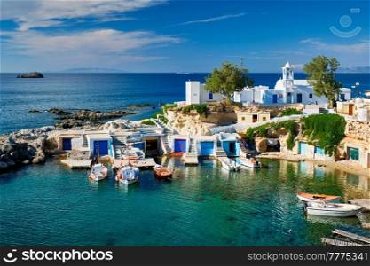 Typical Greece scenic island view - small harbor with fishing boats in crystal clear turquoise water, traditional white houses church. Mandrakia village, Milos island, Greece.. Mandrakia village in Milos island, Greece