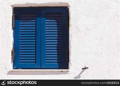 Typical Greek architecture details concept. Blue window shutters on house in Greece.. Greek blue window shutters
